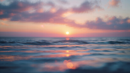 Obraz premium Sun shining over calm ocean waves at sunset with pink and purple clouds