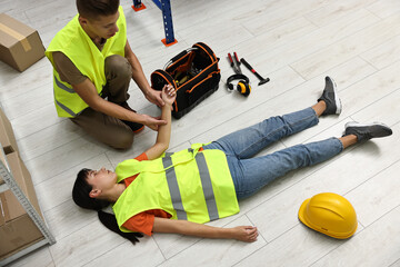 Accident at work. Man checking pulse of his unconscious colleague in warehouse