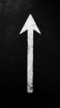 a tall white arrow pointing upward on a dark textured surface creating a bold visual navigation symbol with grit
