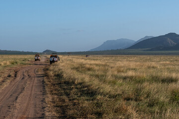 samochody z turystami na safari, Czerwona droga biegnąca przez sawannę w Park Narodowy Tsavo i rezerwat wzgórz Taita, Kenia, Afryka © Kamil_k2p