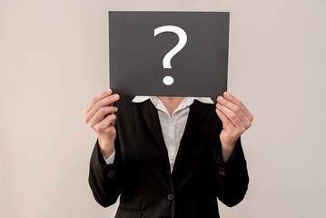 Businesswoman covering face with question mark sign, expressing doubt and uncertainty in business
