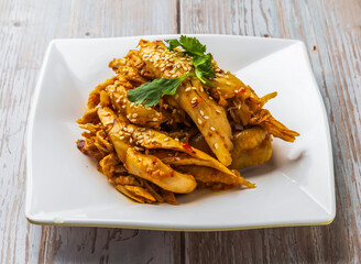 hot and spicy shredded chicken with savory sauce, sesame seeds and cilantro served in plate on Wood Table Close up Side view of Hong Kong food