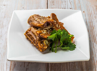 Marinated Goose Wings with savory sauce, sesame seeds and cilantro served in plate on Wood Table Close up Side view of Hong Kong food