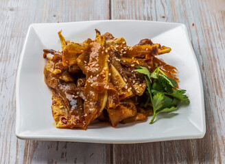 Spicy Pig Ear Salad with a spicy sauce, sprinkled with sesame seeds served in plate on Wood Table Close up Side view of Hong Kong food