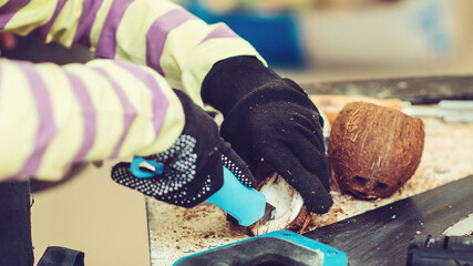 Boy in the workshop makes crafts with coconut. Young carpenter working in craft workshop. Creative student doing his project in workshop.
