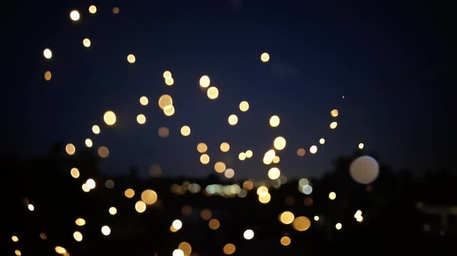 Abstract bokeh lights floating on a dark background, concept of fireflies on a warm summer night