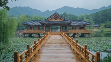 Tranquil wooden bridge leading to a traditional pavilion surrounded by lush mountains