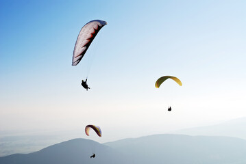 Alone paraglider flying in the blue sky against the background of clouds. Paragliding in the sky on a sunny day.