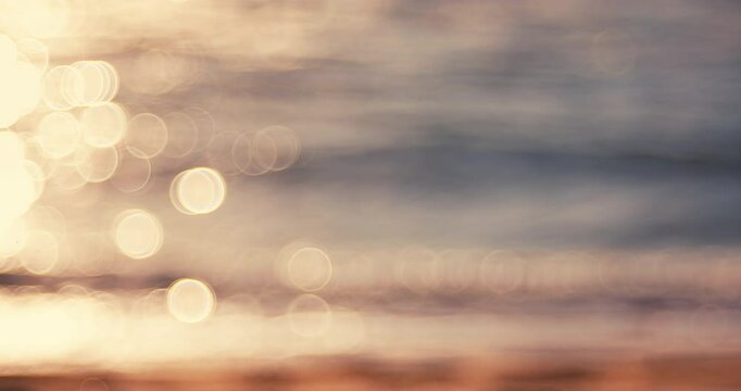 Abstract blur of sunny reflections sunshine bokeh on a calm water surface during beautiful sea sunrise over the beach
