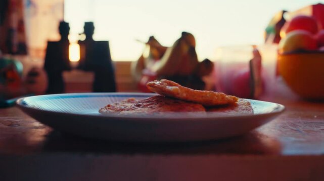 A Person is Putting Sauce on Fried Fish and a Side in a Warmly Lit Kitchen Scene in Kokelv, Norway - Close Up