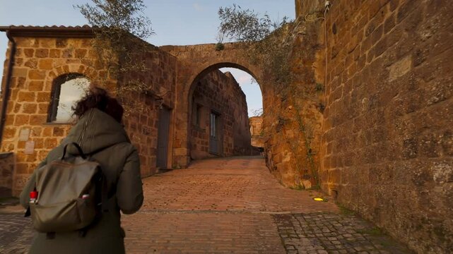 Woman walks through stone arch to enter abandoned Italian village of Celleno