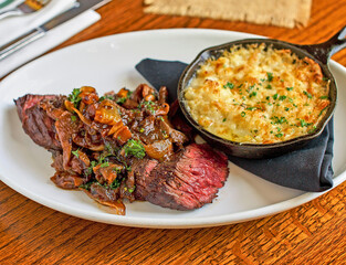 pan seared hanger steak topped with caramelized onions and mushrooms served with potato au gratin