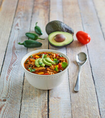 shredded chicken soup topped with fresh avocado and cilantro