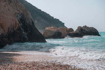 Rocky coastline with turquoise waves crashing on the shore in Kefalonia, Greece