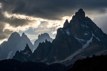 Fototapeta premium Majestic Mountain Peaks Under Dramatic Cloudy Sky at Dusk