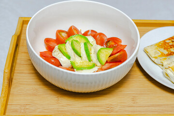 Salad with tomato, cucumber and mozzarella in a white bowl