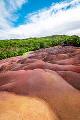 Scenic and beautiful view of amazingly colorful eroded dunes in a tropical jungle clearing at the Seven Colored Earth Geopark in Chamarel, Mauritius