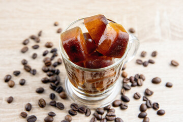 Side view of coffee ice cubes scattered on table, decorated with coffee beans. Studio shot. Concept of coffee ice cubes for making iced coffee.