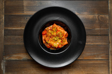 Paccheri with cherry tomatoes and crispy topping in a black plate
