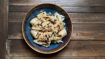 Paccheri with breadcrumbs and black truffle on a rustic ceramic plate