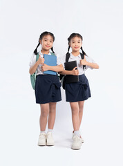 Obraz premium Schoolgirls in uniform give thumbs up, ready for class. Cheerful kids with books and backpacks pose.