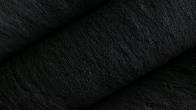 Black stone surface rotation showcasing folded wrinkles, organic grain, and layered creases in a luxurious premium style