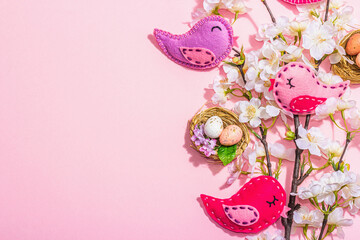 Gentle Easter composition with cherry flowers and handmade felt birds. Decorative eggs and nest