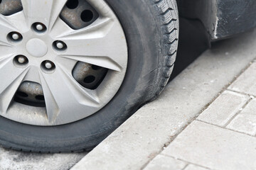 Tire crumpl, damage and squeeze by wrong parking, close-up. Car tire parked close to the curb. Car...