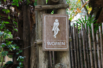selective focus Wooden sign for women's restroom written in white. A cafe restroom in a deep forest decorated in a shady, natural style with space for text.