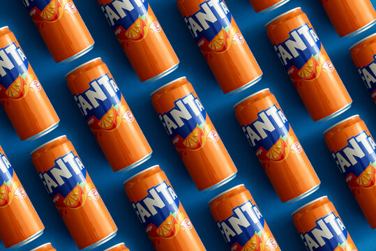 Lviv, Ukraine - February 26, 2025: Close-up of Fanta Orange drink cans lying on paper background.  Texture. Top view