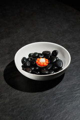 top view of haute cuisine concept dish dessert orange white macarons on black stones in white plate on grey stone background 