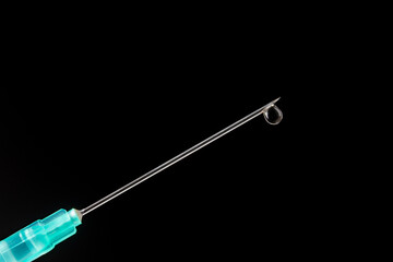 Syringe needle with an injection solution on black background, copy space, closeup. Syringe with vaccination, macro. Liquid medication or drug