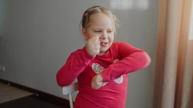 Confident young girl raising her fists and dancing with excitement. Child expressing joy, triumph, and enthusiasm. Close-up of strong, energetic attitude and celebration of success
