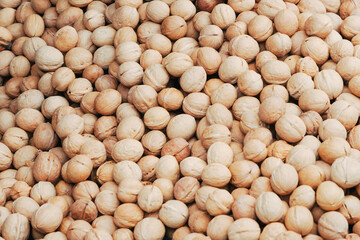 A close-up view of a large pile of walnuts in their shells. The natural texture and earthy tones emphasize their organic, raw, and nutritious qualities, perfect for a healthy diet.