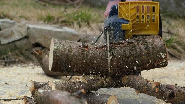 A man using a chainsaw to cut a log or tree