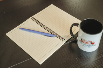 Blank notebook with a pen and a cup of coffee