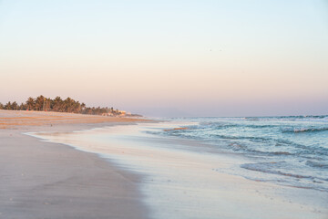 Pastellfarbener Sonnenuntergang am Strand in Salala Oman