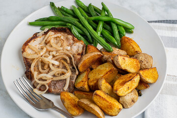 pork chop top with onions  with green beans and potato wedges