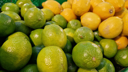 Limes close-up with selective focus. Heaps of tasty limes for sale in a store. Variety of fresh produce. Ripe limes for sale in a supermarket. Ripe, juicy, green fruits with vitamin C