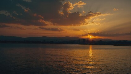Dramatic Sunset Over Serene Water with Distant City Skyline and Radiating Sunbeams