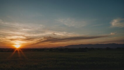 Fototapeta premium Golden Sun Illuminating a Vast Green Field at Dusk with Distant Hills and a Dramatic Sky