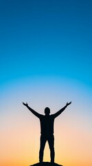 Fototapeta premium Silhouette of man with raised arms against vibrant blue and orange sunset sky, standing on hill expressing freedom, achievement and life success.