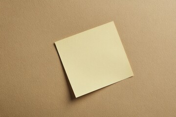 A yellow square paper on a textured brown background surface