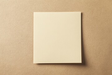 A single blank cream colored square paper on brown textured surface