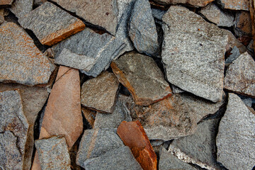 Close up view of a pile of black and brown rock stones. Texture of stone wall background for design.