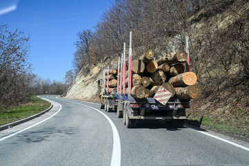  Timber truck with crane on the road. Logs on the truck. A truck is transporting wood. Export of...