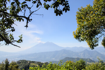 view of scenic volcanoes surrounded by trees in a famous public park in antigua guatemala (agua fuego acatenango volcano peaks mountains) hiking trail hike outdoor ecotourism travel outdoor adventure