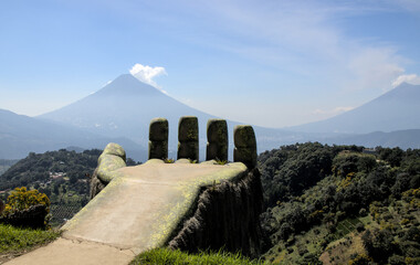 large hand sculpture in antigua guatemala with view of agua fuego and acatenango volcanos in the...