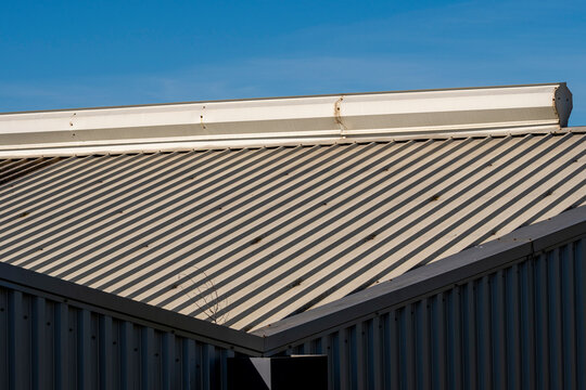 Industrial roof detail with a sharp geometric structure under a blue sky. A minimalistic composition capturing the essence of industrial and modern design.