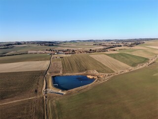 Newly built retention pond and sluice gate between agricultural fields aerial panorama landmark